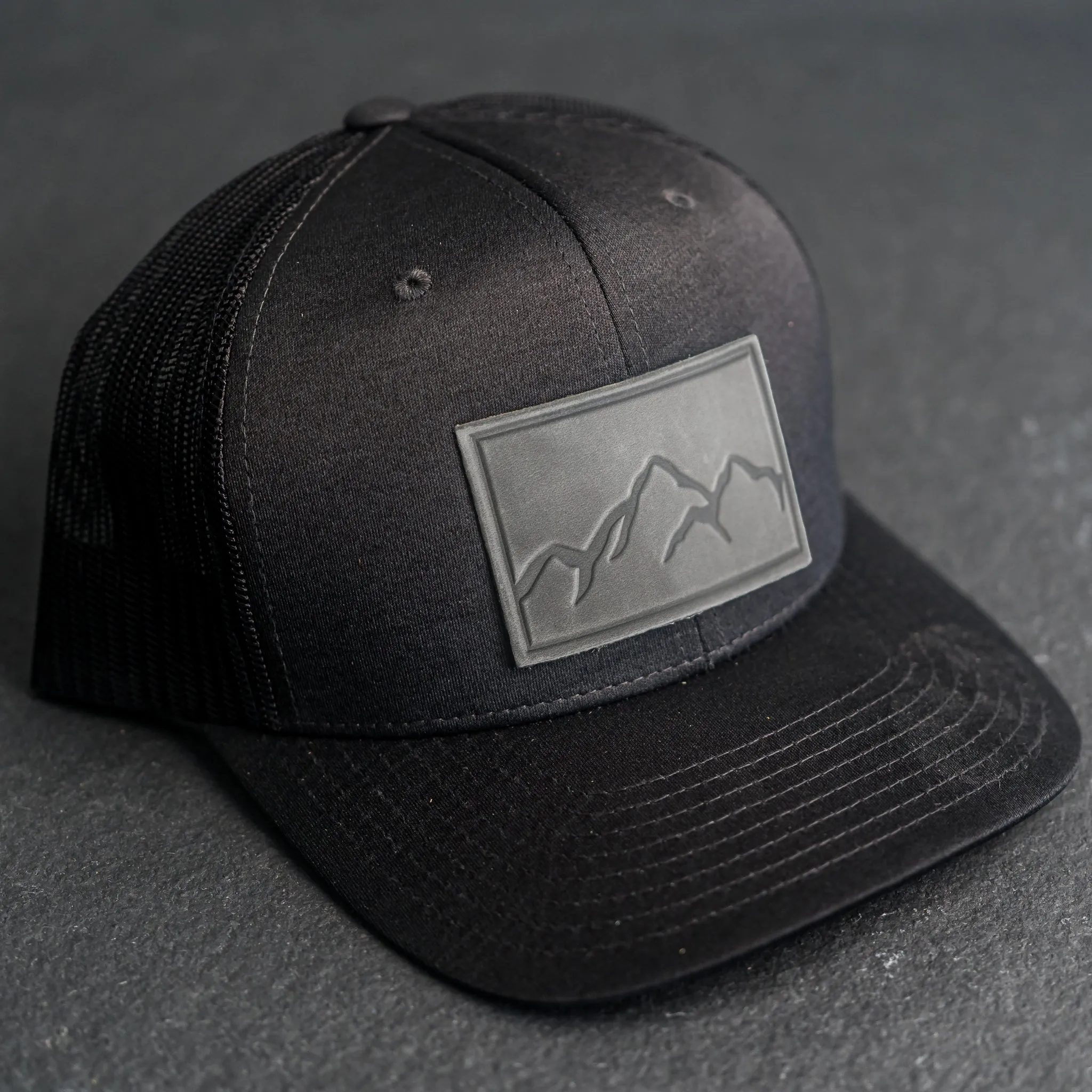 Leather Patch Performance Style Trucker Hat - Mountain Range Stamp